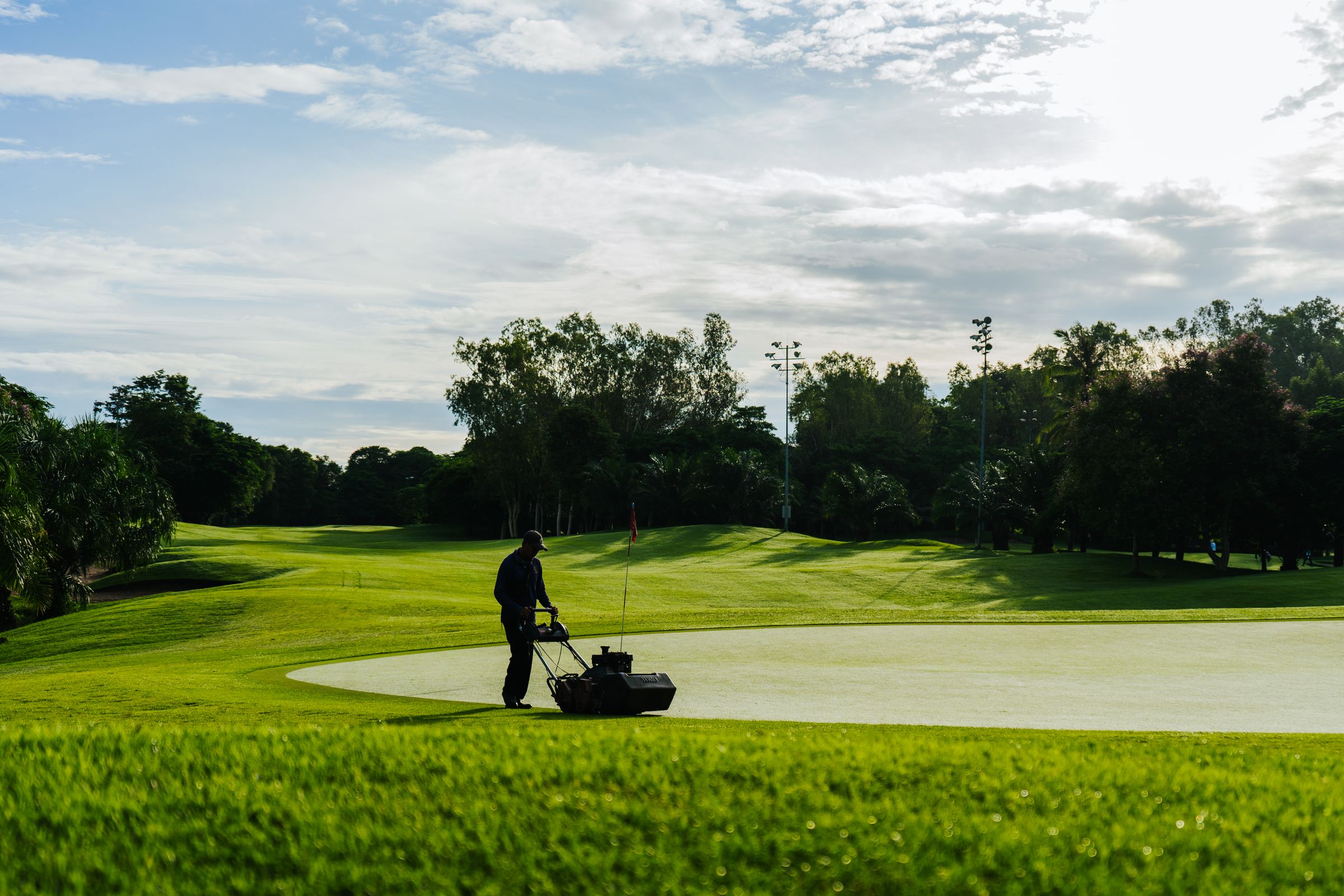 A greenskeeper mowing a golf course putting green