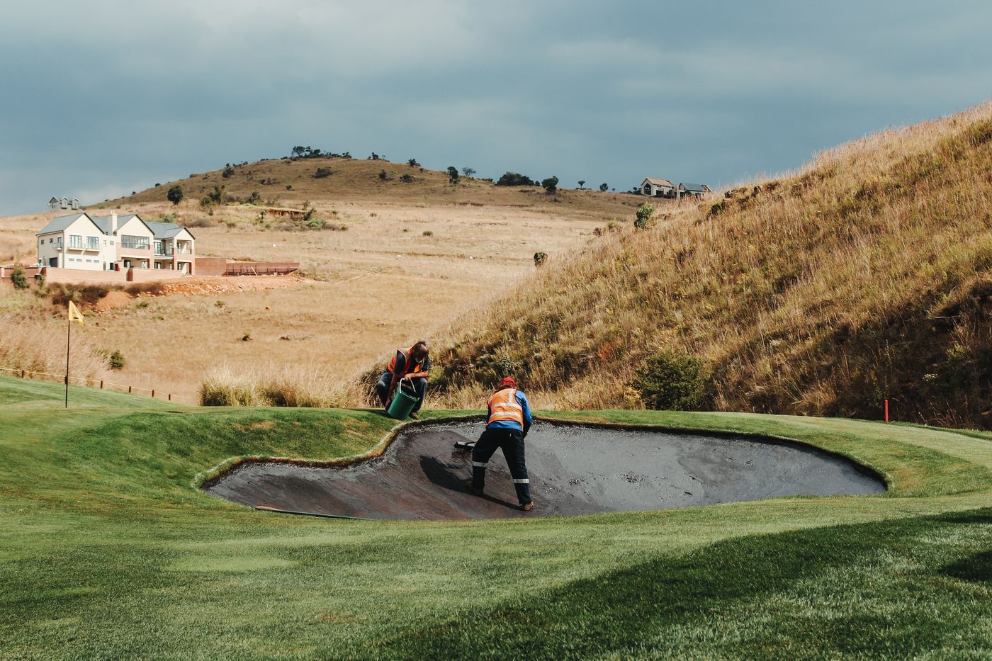 Grounds crew maintaining a bunker on a golf course